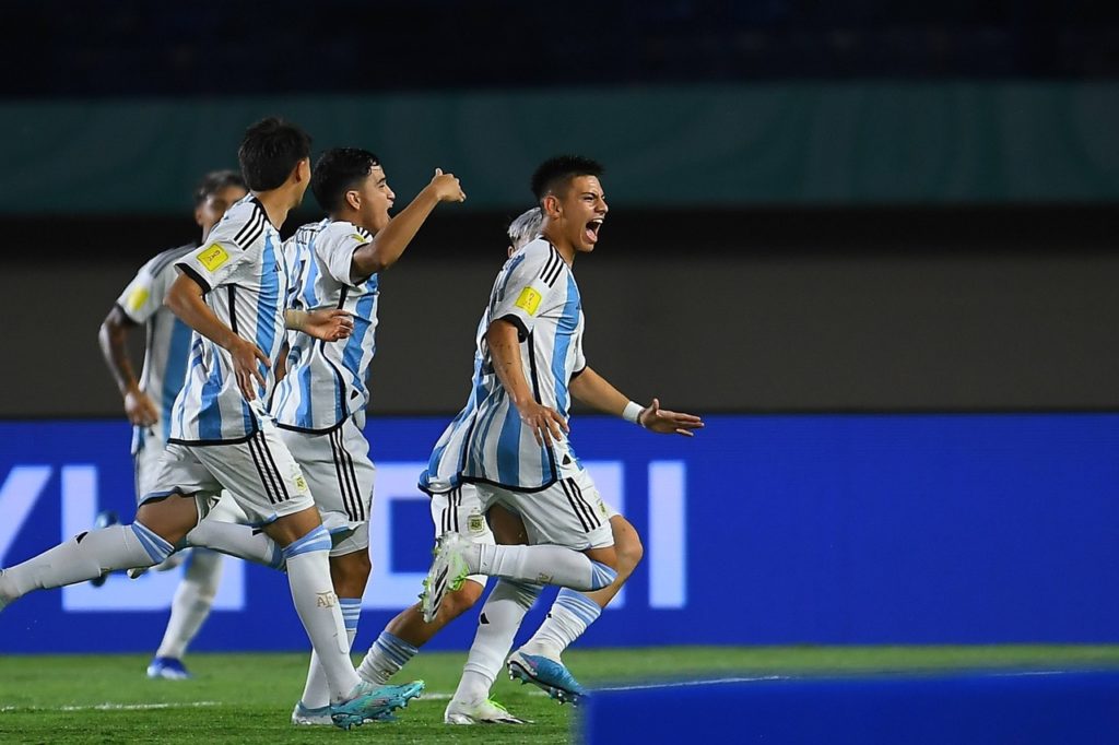 Echeverri, meia da seleção da Argentina, corre com o uniforme de seu país ao lado de seu compaheiros.