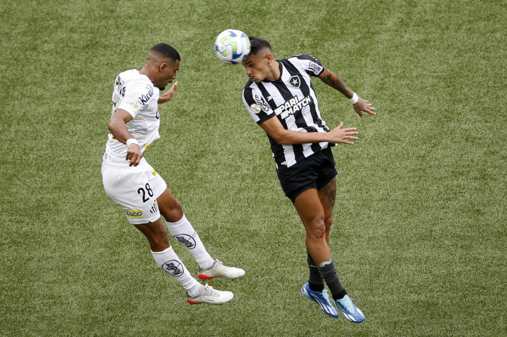 Tiquinho Soares, jogador do Botafogo, e Joaquim, do Santos, disputam uma bola durante uma partida entre as equipes.