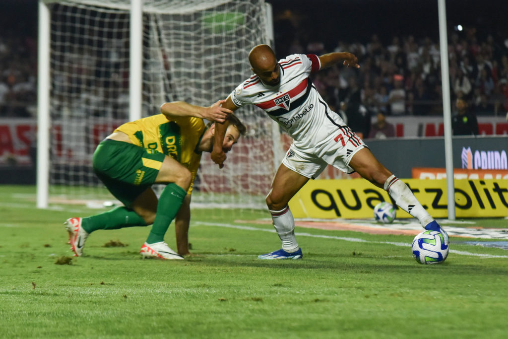 Lucas, meia do São Paulo, disputando uma bola contra o adversário em um jogo de seu clube.