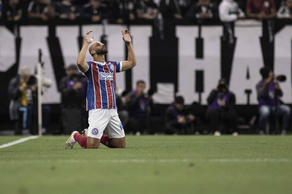 Thaciano, meio-campista do Bahia, ajoelhado no chão durante uma partida do time.