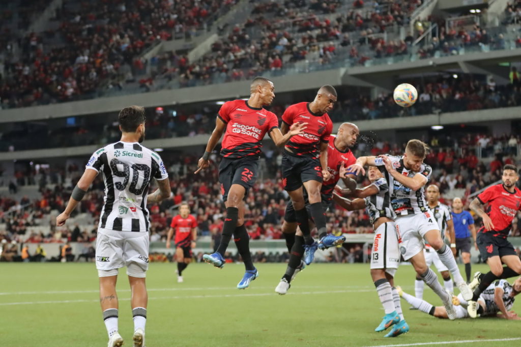 Madson, Erick e Fernandinho, do Athletico, sobem e tentam cabecear a bola para o gol durante uma partida do time na temporada.