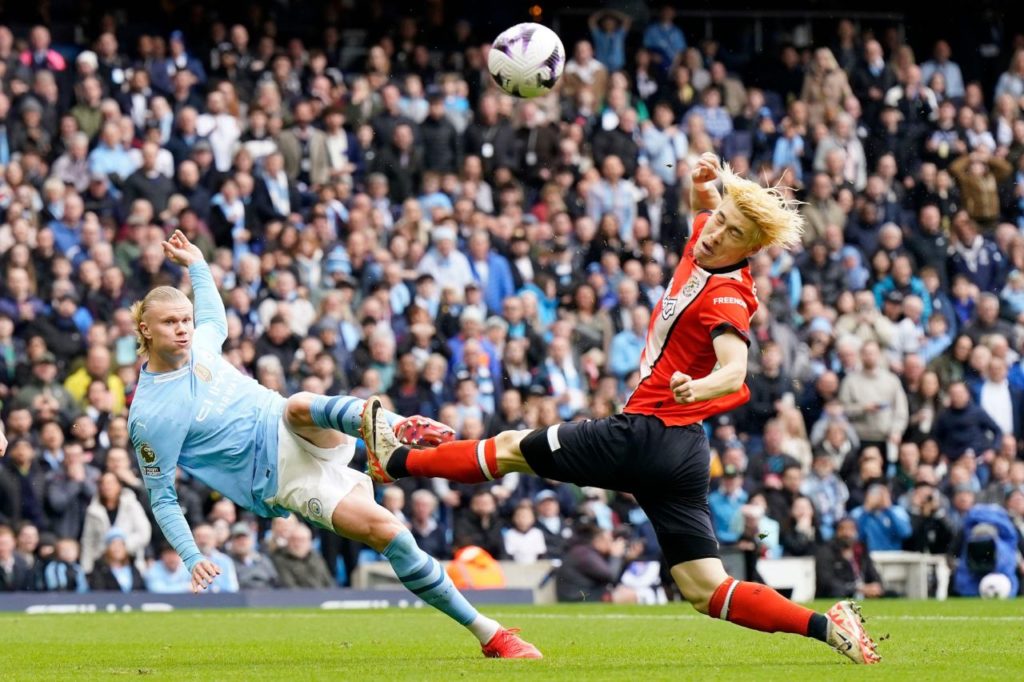 Centroavante Erling Haaland finalizando a bola no rosto do zagueiro Hashioka do Luton Town