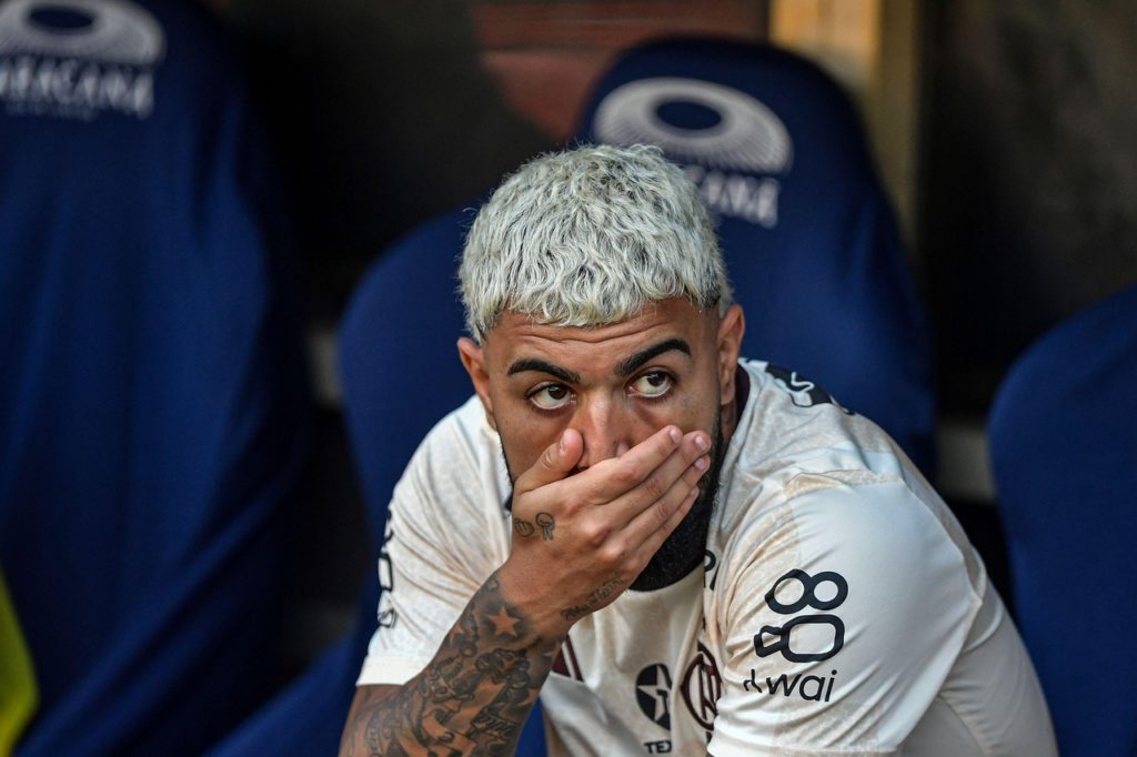 Gabriel, do Flamengo, com a mão na boca observando o jogo do banco de reservas.