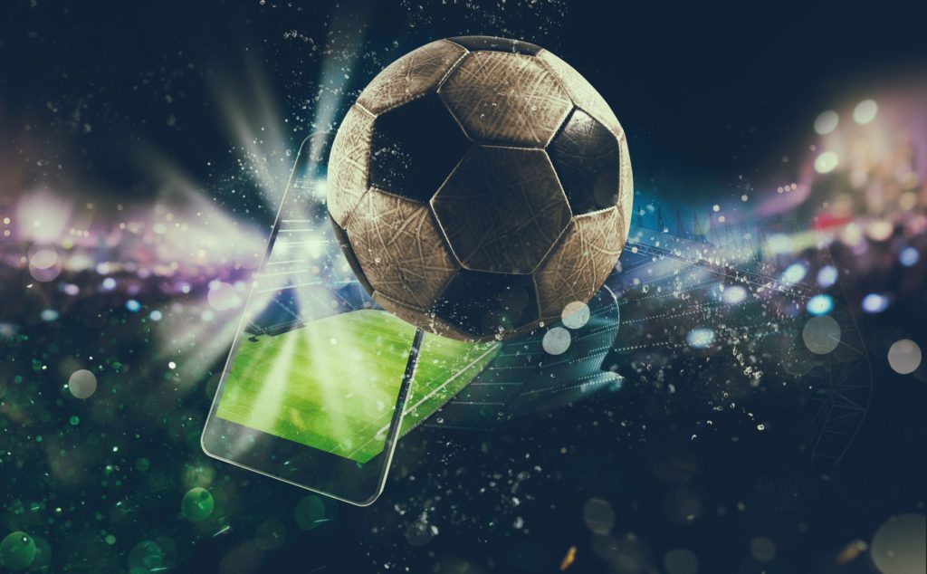 Imagem ilustrativa com uma bola de futebol e um celular, simulando apostas em esportes.