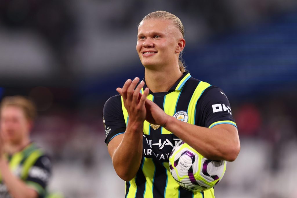 Erling Haaland carregando a bola depois de marcar três gols em um jogo da Premier League.