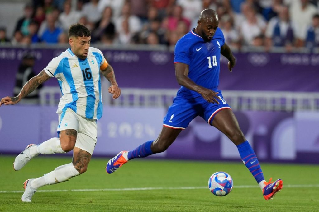 Atacante Mateta sendo marcado pelo zagueiro Otamendi no jogo entre França e Argentina nos Jogos de Paris-2024