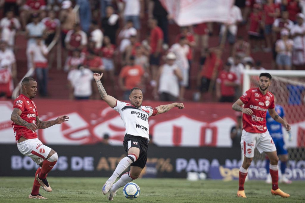 Douglas Baggio, do Botafogo-SP, disputando a bola com dois jogadores do Vila Nova em um jogo da Série B de 2024.